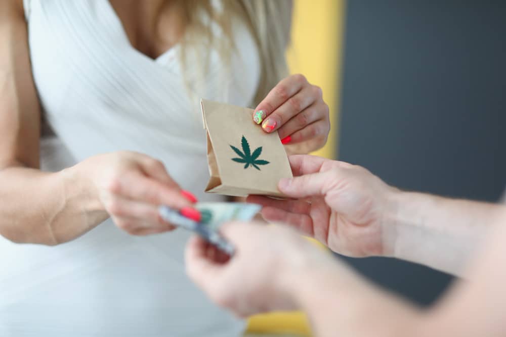 Doctor Handing Patient a Small Brown Bag with Marijuana Symbol