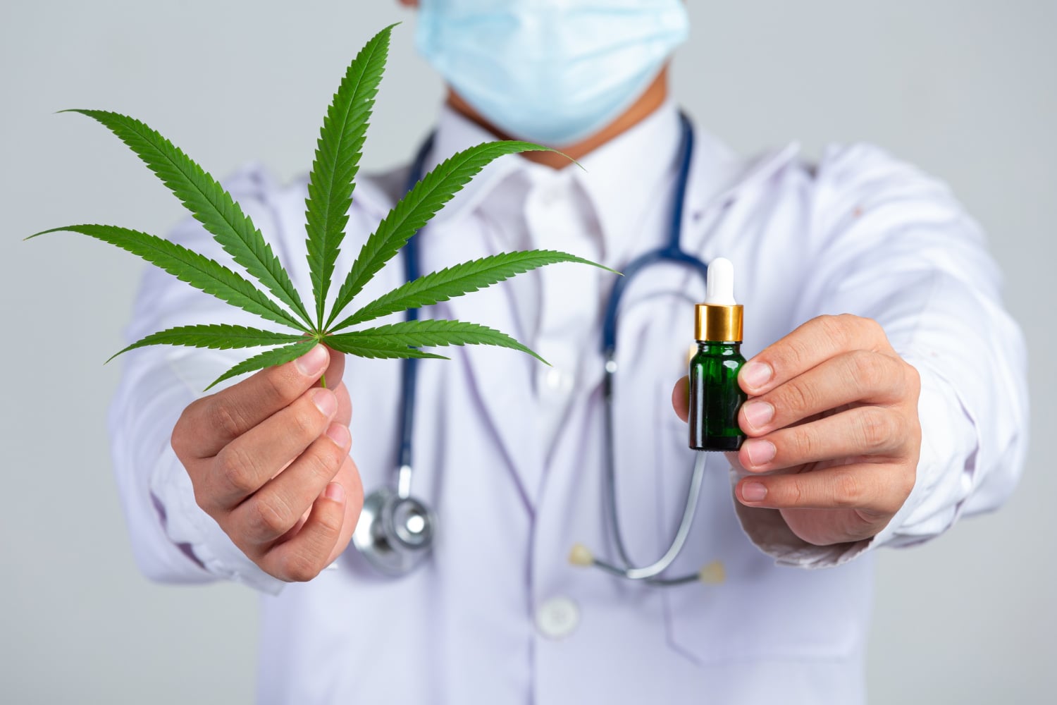 Doctor Holding Marijuana Leaf and Green Tincture Bottle